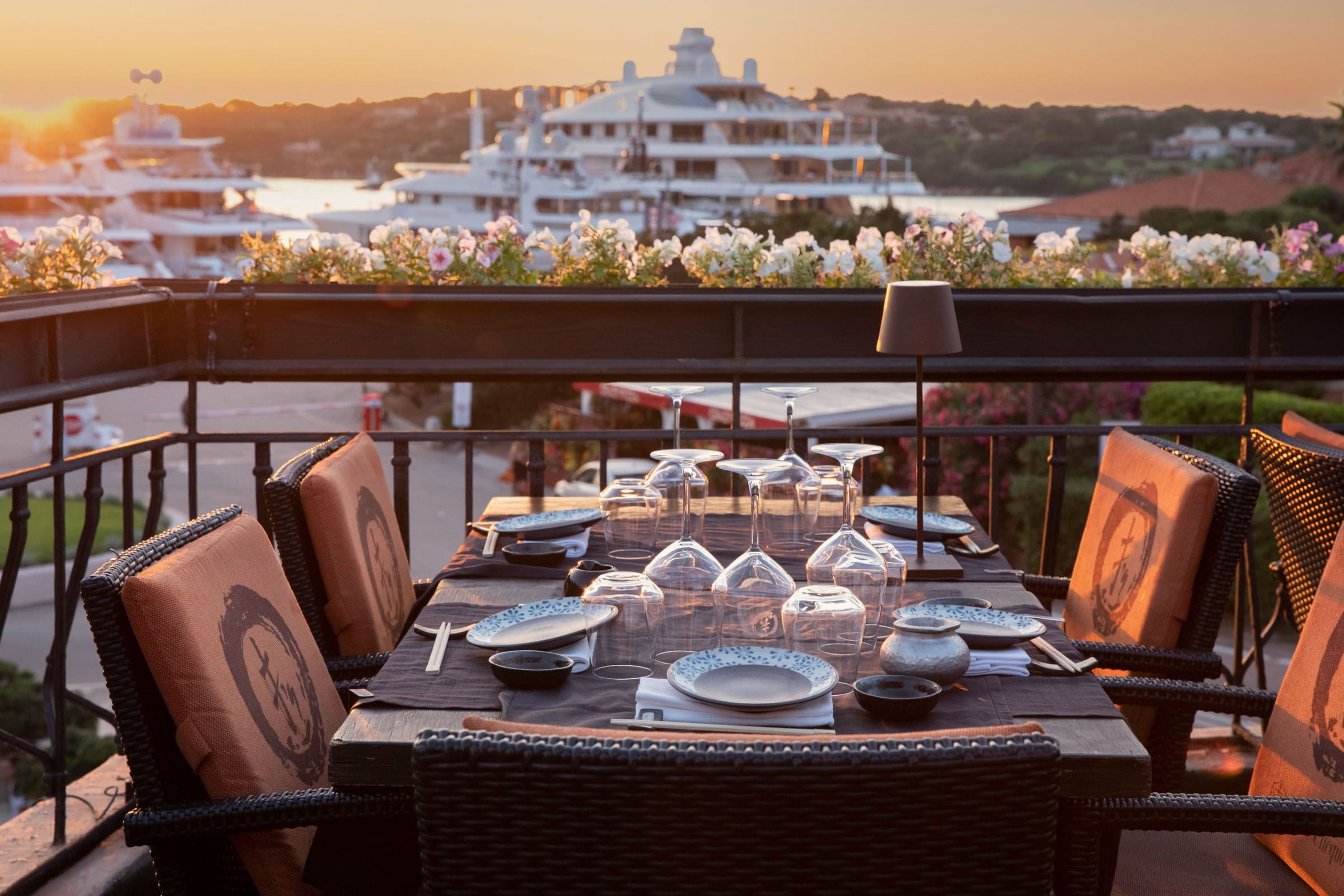 Cena elegante al tramonto con vista su yacht a Porto Cervo.